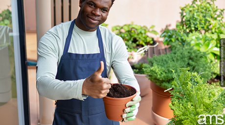 a man with a pot full of soil on the terrace makes a thumbs-up gesture